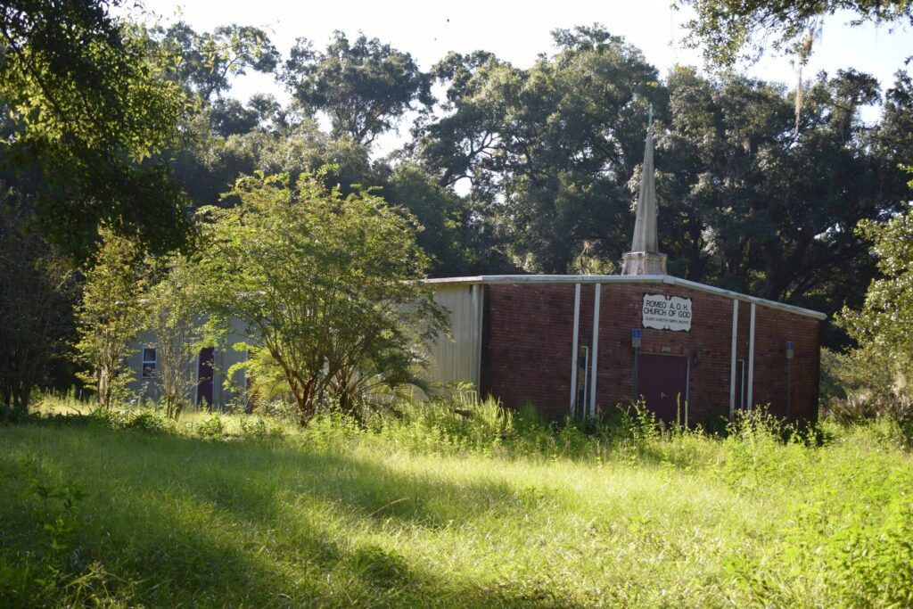 Romeo A.O.H. Church of God surrounded by trees and overgrown grounds in Romeo, Florida