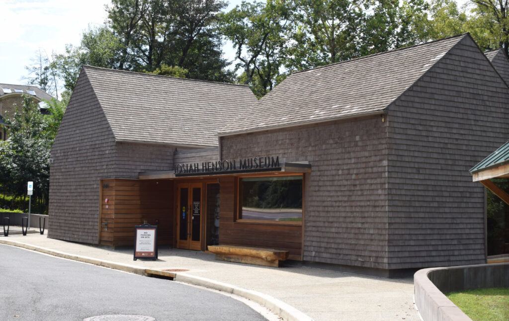 Front entrance of Josiah Henson Museum & Park in North Bethesda Maryland with portrait of Josiah Henson and text “The Real Uncle Tom.”