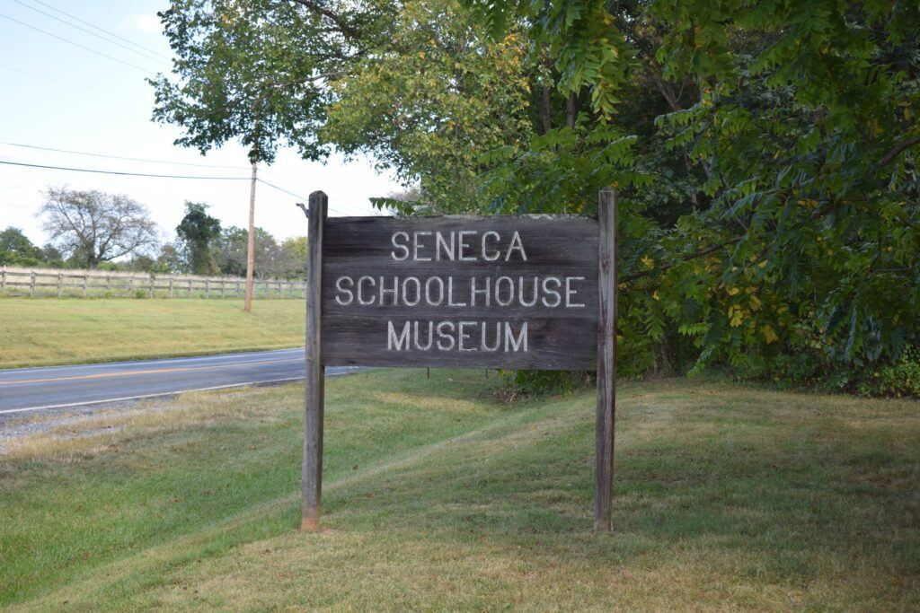 Old wooden fence near the fence line stating: Seneca Schoolhouse Museum.