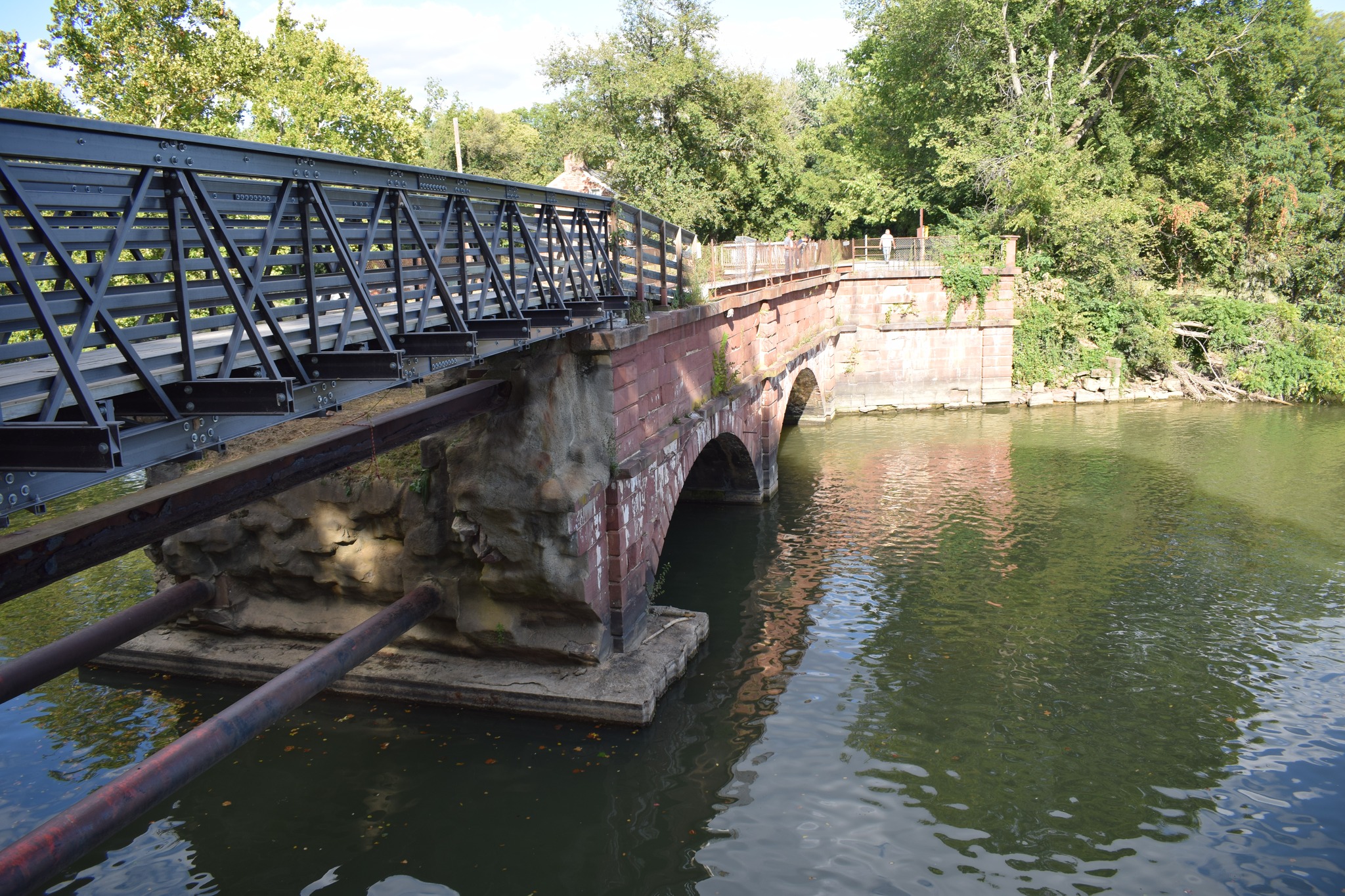 The red-sandstone arches of the Seneca Aqueduct glowing in evening light, carrying the C&O Canal over Seneca Creek.
