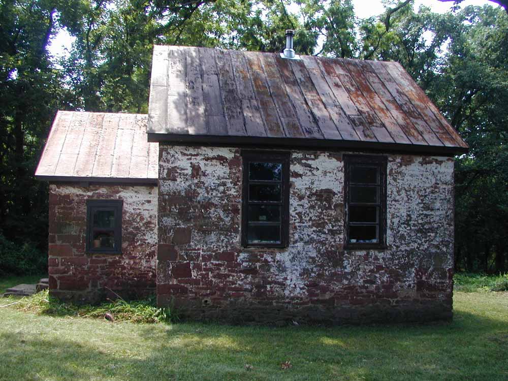 The Seneca Schoolhouse sits abandoned with the rusted tin roof and broken windows.