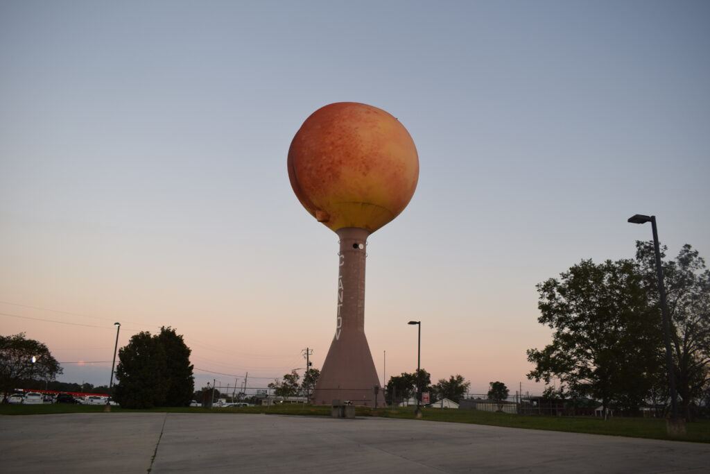 A side-angle view of the Peach Water Tower slightly revealing its famously rounded “peach butt” shape beneath the painted skin.