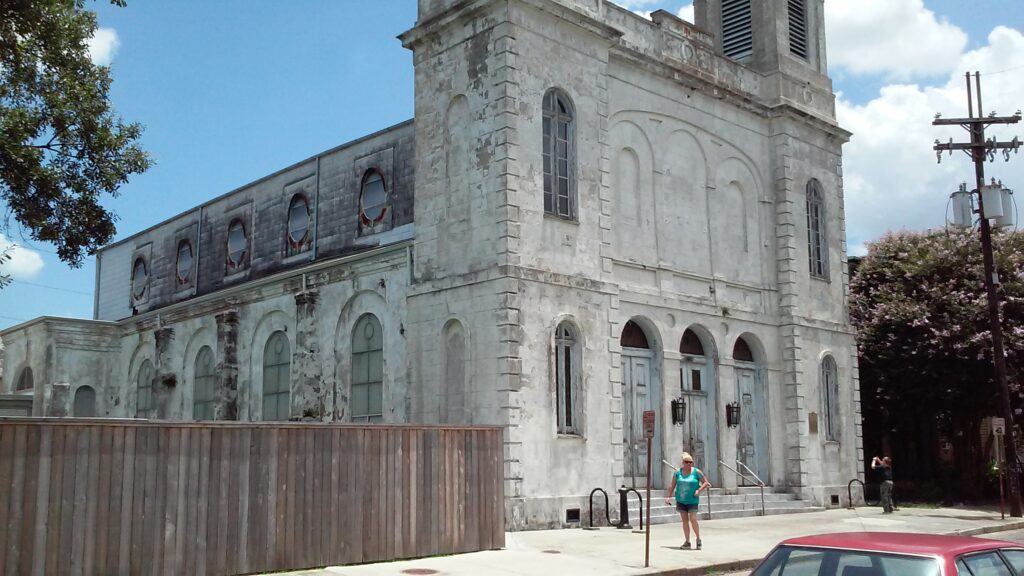 Front view of Holy Trinity Church in the Faubourg Marigny, an abandoned 19th-century German Catholic church with distinctive onion domes and worn brick façade.