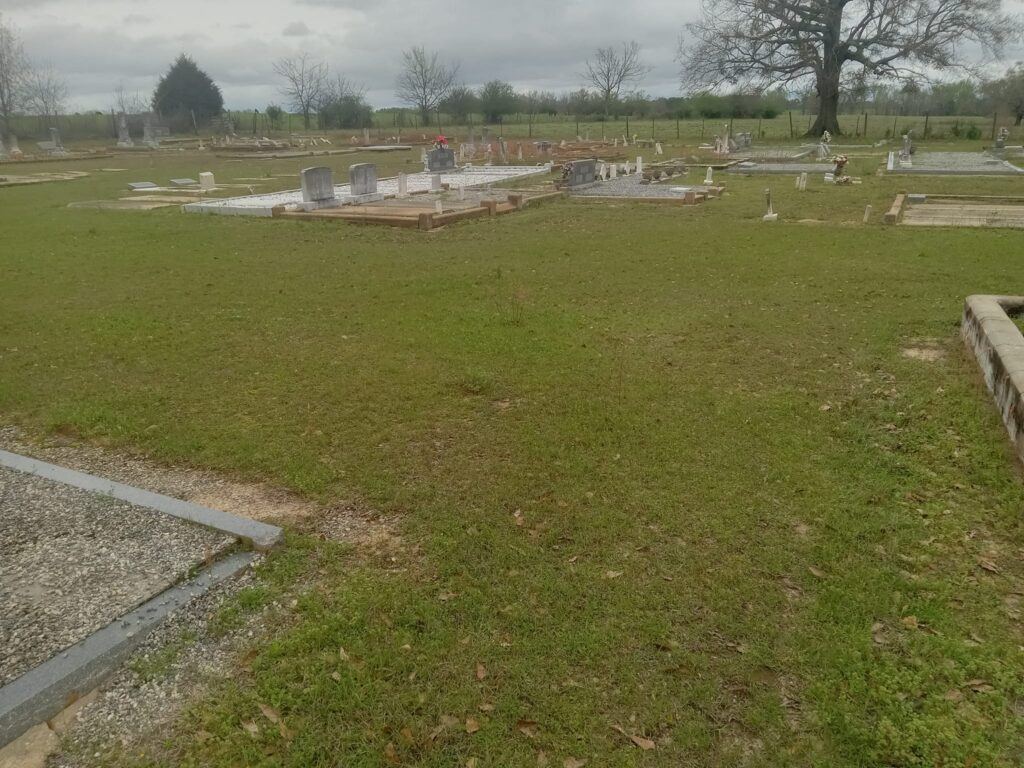 Panther Creek Baptist Church Cemetery in rural Alabama, with headstones surrounded by grass and mature trees.