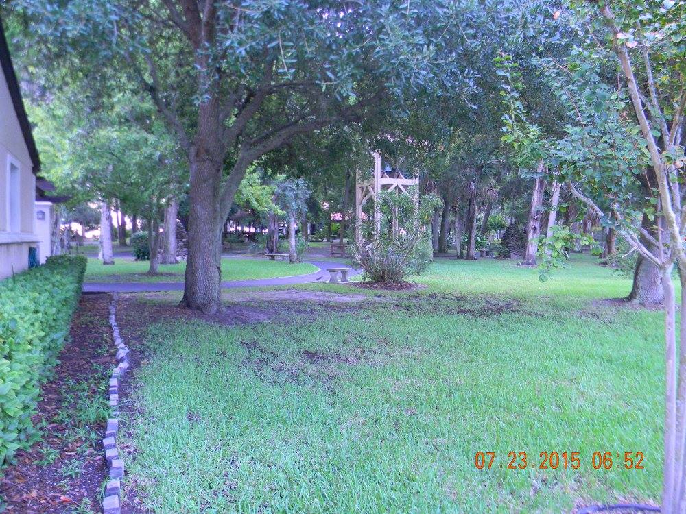 View through a closed gate at Mission Nombre de Dios in St. Augustine, Florida, showing trees, benches, and a walking path inside the historic grounds.