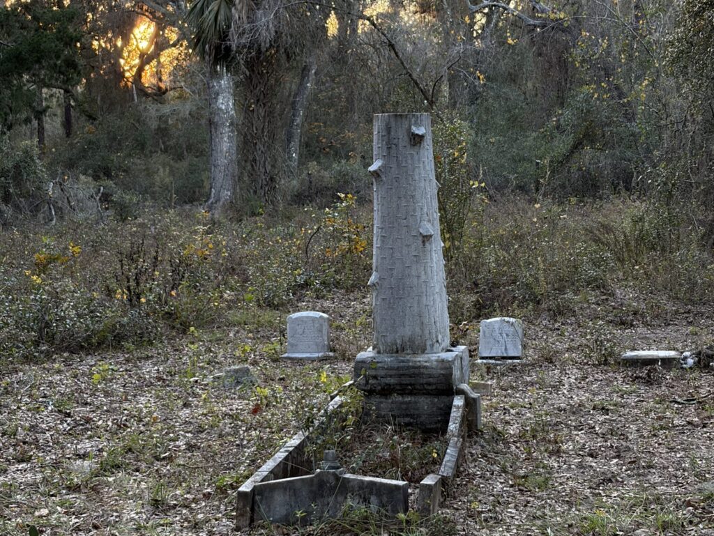 Broken obelisk-style grave marker surrounded by smaller headstones at the Oriole / Giddens Homestead Cemetery in Hernando County, Florida, reflecting loss in a late-1800s pioneer community.