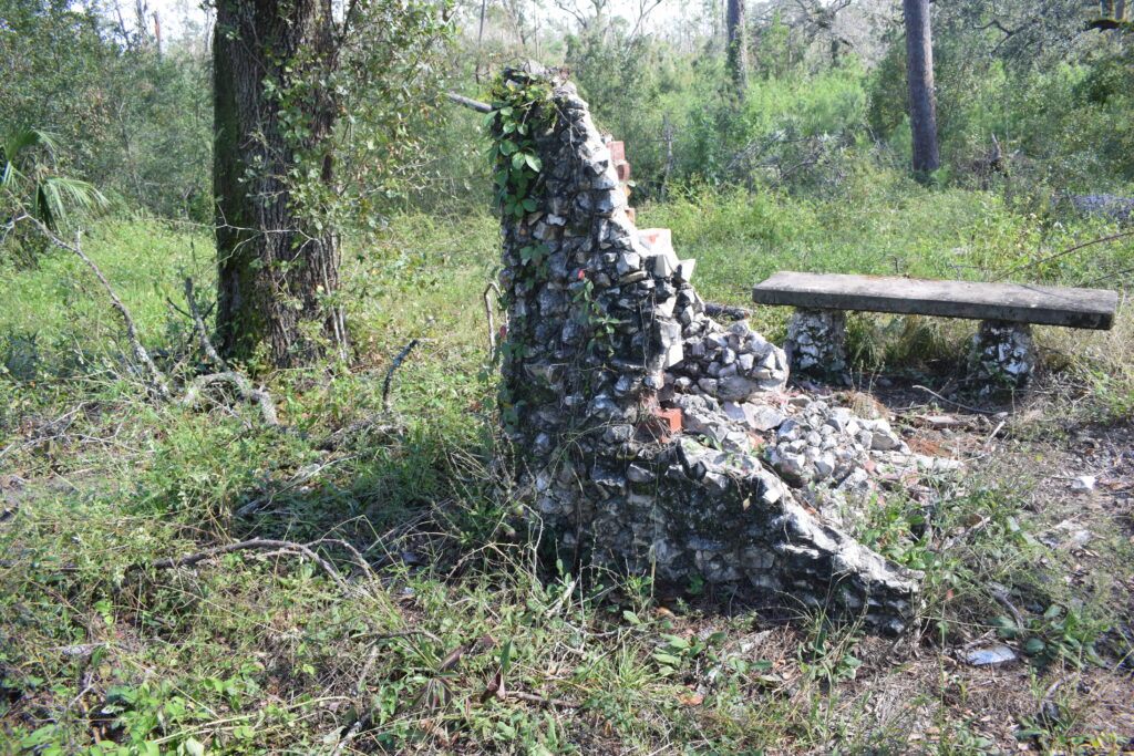 Remains of a stone structure at Ellaville Ghost Town in Florida, partially reclaimed by vegetation near a picnic area.