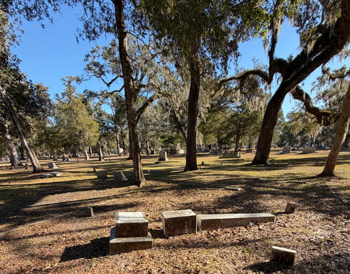 Historic Brooksville Cemetery in Brooksville, Florida, with weathered headstones beneath large oak trees draped in Spanish moss.