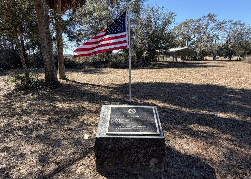 American flag flying above the historical marker at Loyce Cemetery in Pasco County, Florida, the last remnant of the lost town of Loyce.