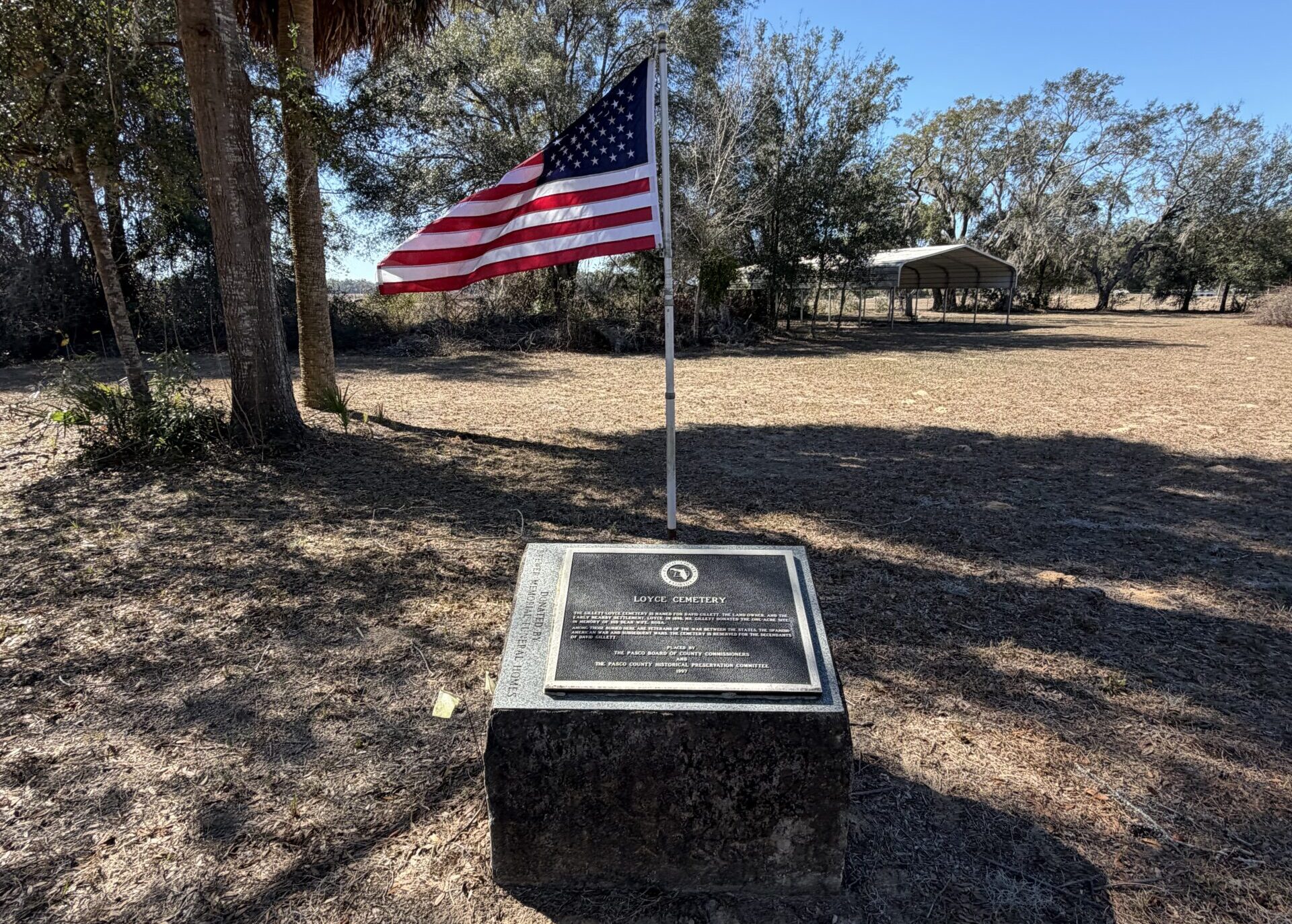 American flag flying above the historical marker at Loyce Cemetery in Pasco County, Florida, the last remnant of the lost town of Loyce.