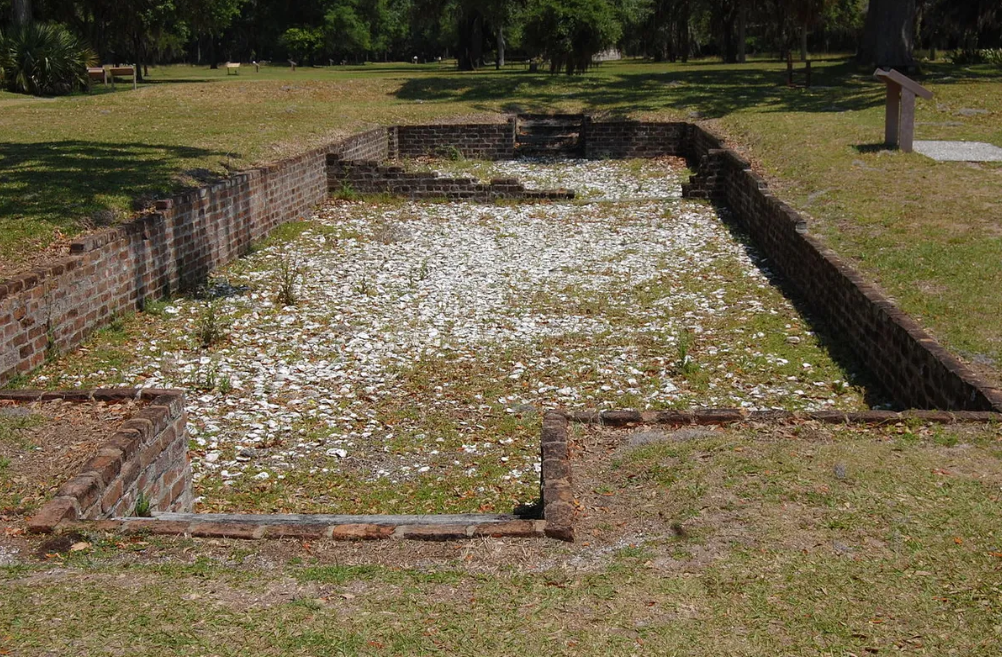 Brick foundation walls and tabby shell debris marking the remains of a colonial-era building at Fort Frederica National Monument.
