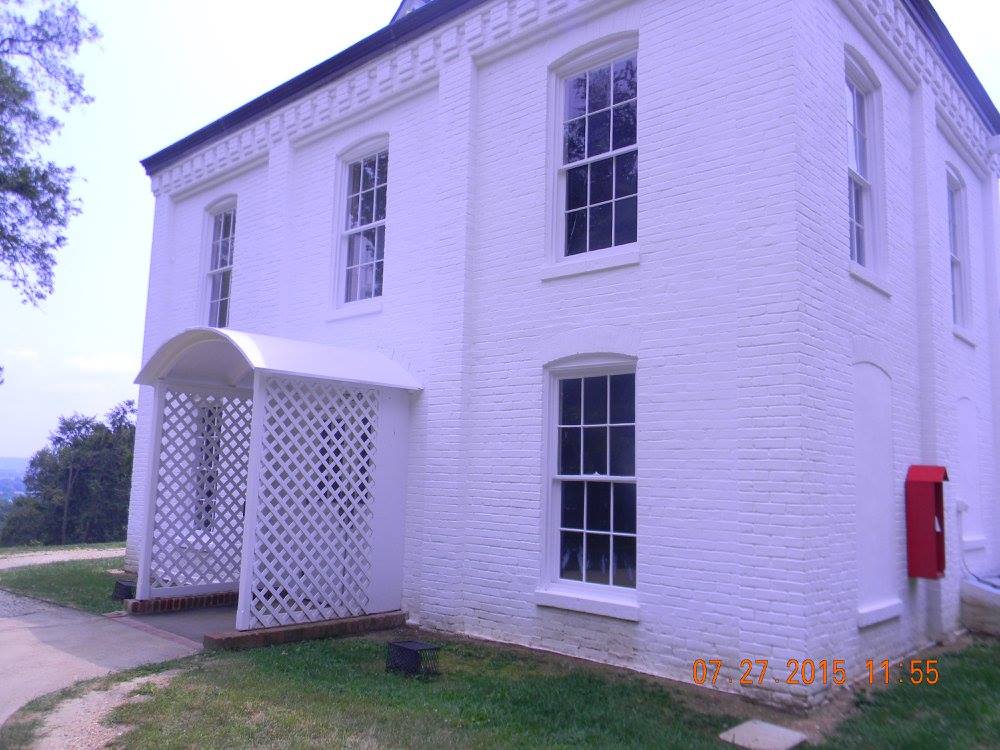A small white brick outbuilding at Arlington House with tall windows and a lattice-covered entryway, representing the lesser-seen structures that supported life on the historic estate.