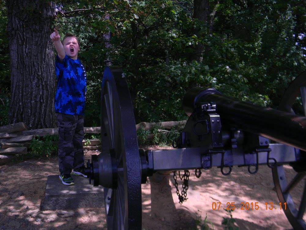 Child pointing dramatically beside a Civil War cannon at Little Round Top in Gettysburg National Military Park