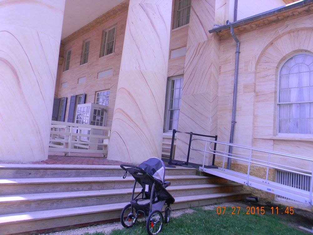 A stroller sits at the base of the large columns of Arlington House, with historic sandstone walls and entry steps visible, capturing a quiet personal moment during a visit to the site.
