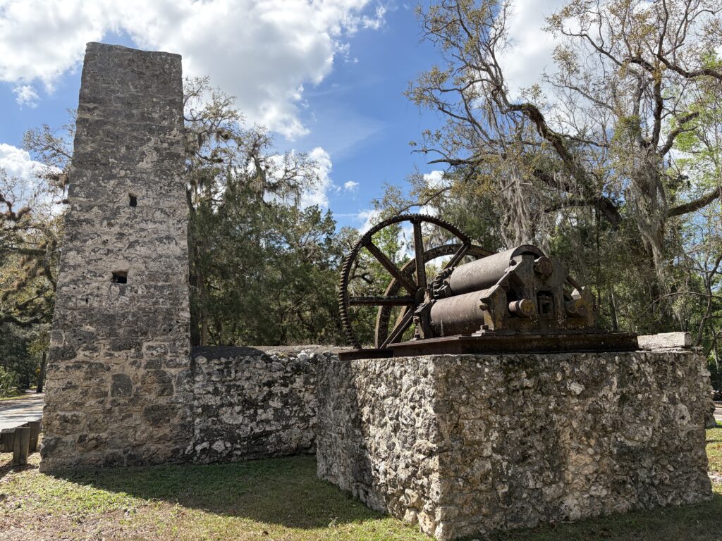 Stone chimney and rusted sugar mill machinery at the Yulee Sugar Mill Ruins Historic State Park in Homosassa, Florida.