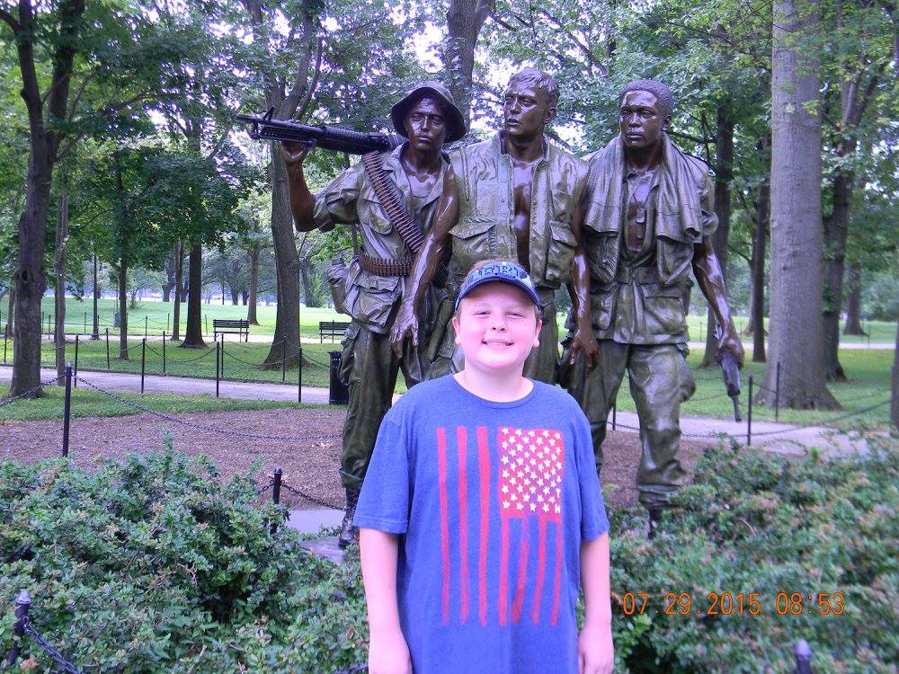 A young visitor stands in front of the Three Servicemen statue at the Vietnam Veterans Memorial in Washington, D.C.
