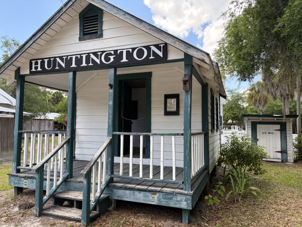 Historic white wooden Huntington Post Office building with green trim and front porch at Barberville Pioneer Settlement in Florida.
