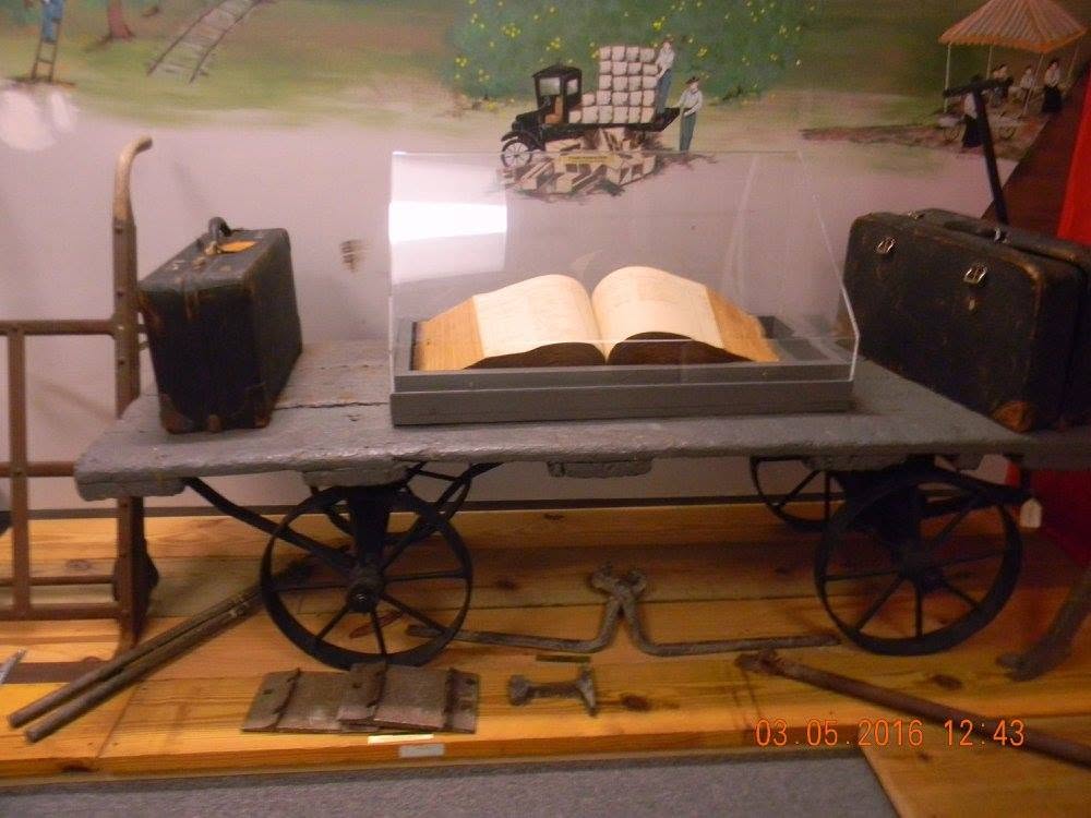 Historic exhibit featuring an open book, vintage luggage, and an antique handcart at the Brevard Museum of History and Natural Science in Cocoa, Florida.