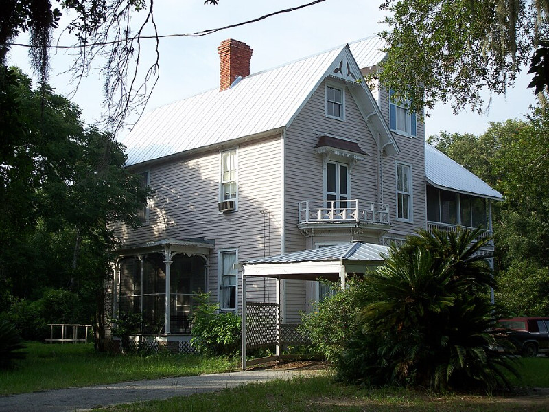 Side view of the historic Thomas R. Ayer House in Oklawaha, Florida, showcasing its restored Queen Anne architecture surrounded by mature trees.