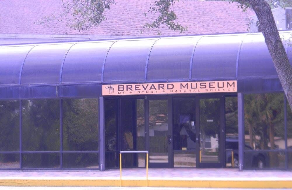 Front entrance of the Brevard Museum of History and Natural Science in Cocoa, Florida, with the museum sign displayed above the glass entrance doors.