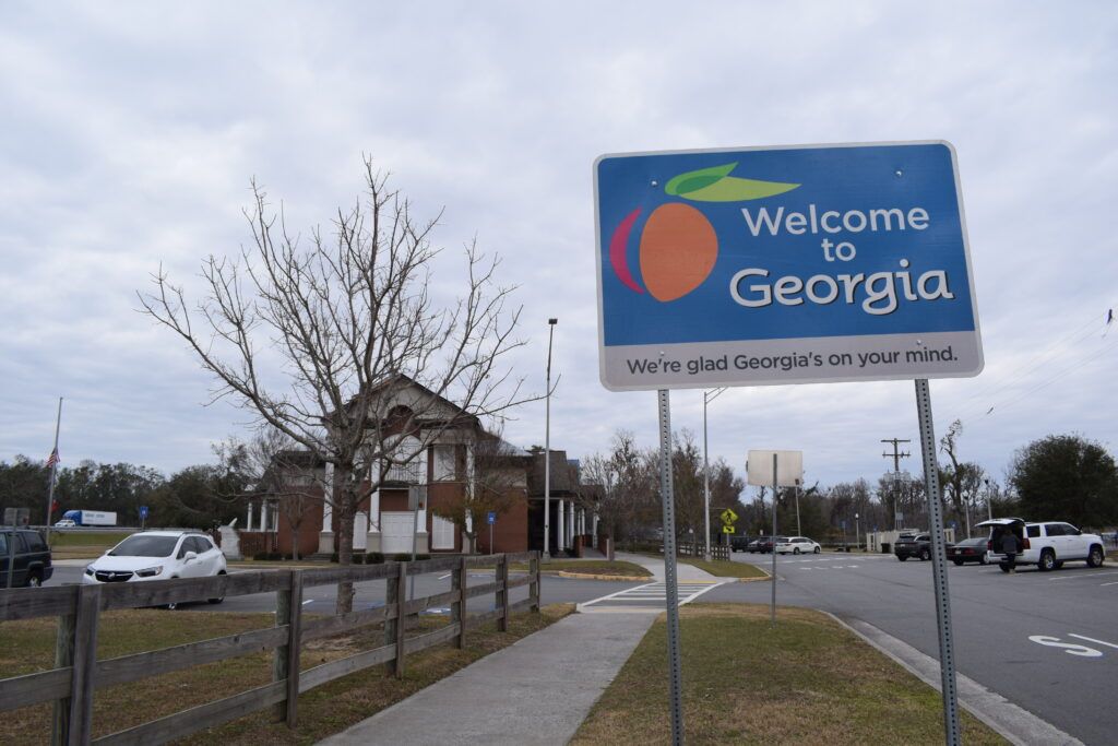 Blue "Welcome to Georgia" roadside sign outside the Georgia Welcome Center near the Florida state line on an overcast day.