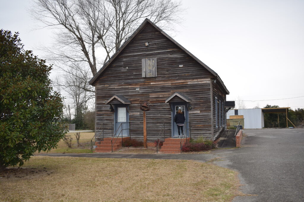 Exterior of the Georgia State Cotton Museum in Georgia with a visitor walking toward the entrance on an overcast winter day.