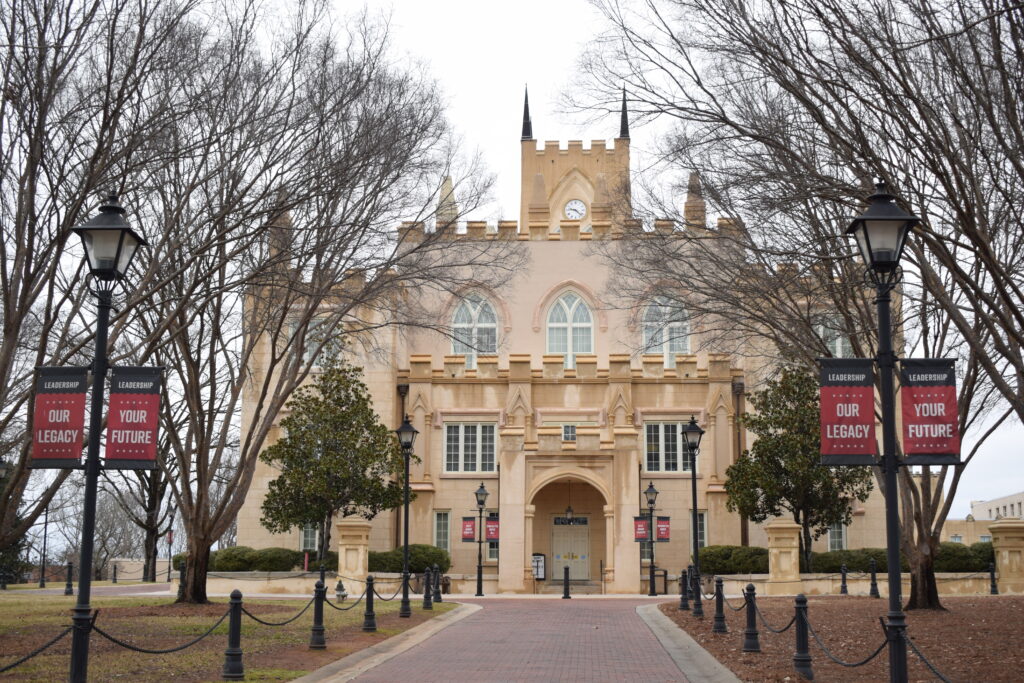 The former Georgia State Capitol building in Milledgeville, Georgia, now home to Georgia Military College, framed by bare winter trees and historic lampposts.