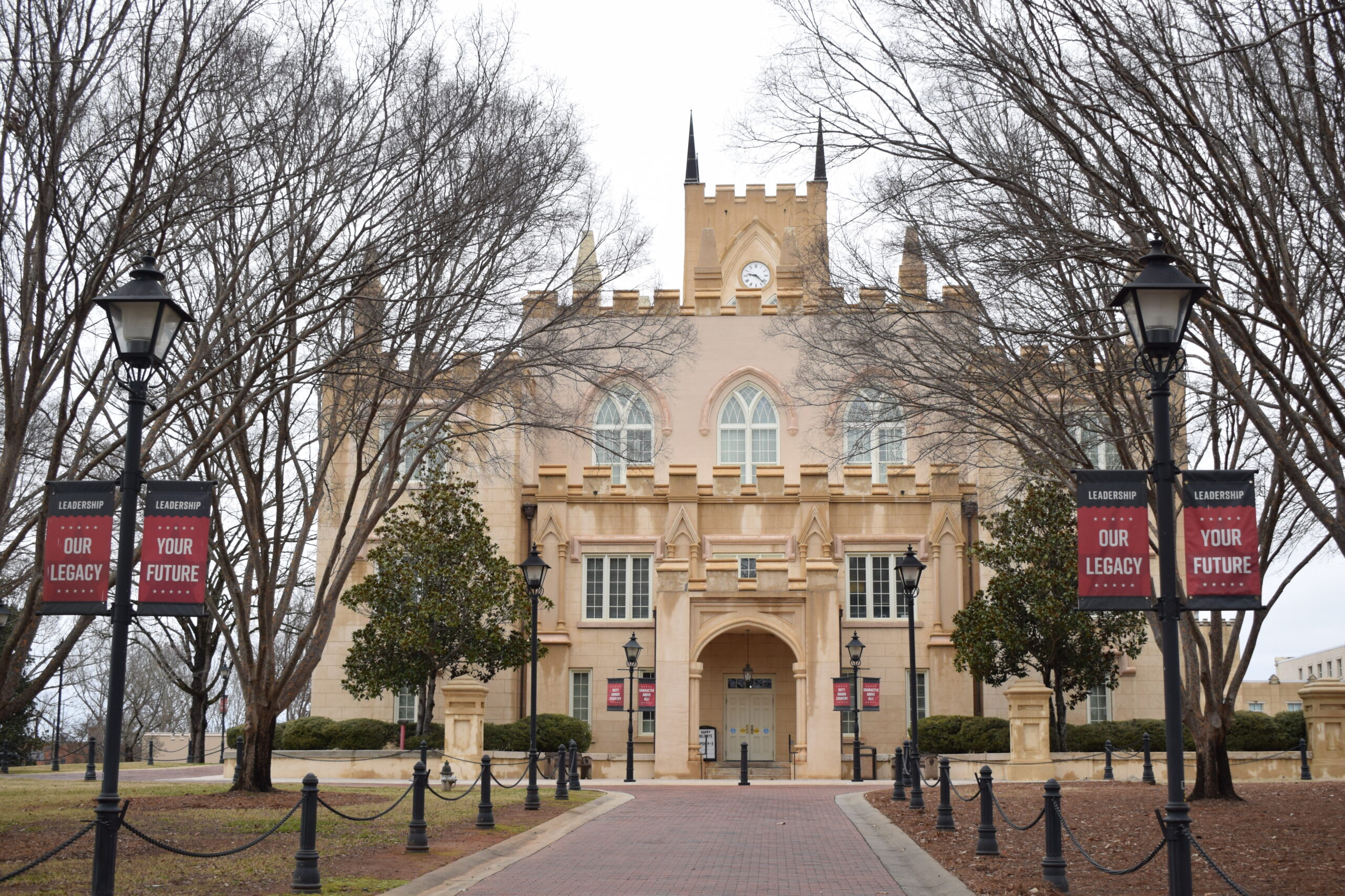 The former Georgia State Capitol building in Milledgeville, Georgia, now home to Georgia Military College, framed by bare winter trees and historic lampposts.