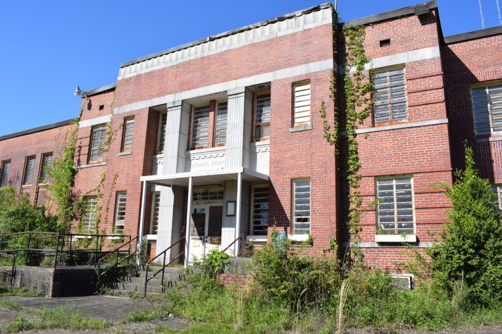 The historic Richard B. Russell Building at Central State Hospital in Milledgeville, Georgia, showing its brick façade, overgrown entrance, and abandoned appearance.