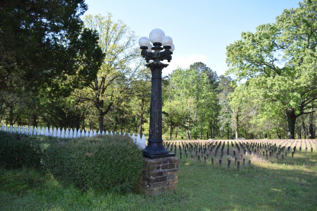 Historic patient cemetery at Central State Hospital in Milledgeville, Georgia, with rows of numbered grave markers beneath mature trees.
