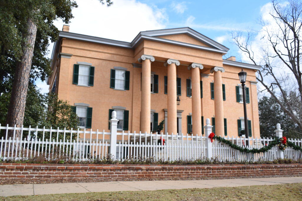 Georgia's Old Governor's Mansion in Milledgeville, Georgia, a beautifully preserved Greek Revival home with towering columns, green shutters, and a white picket fence.