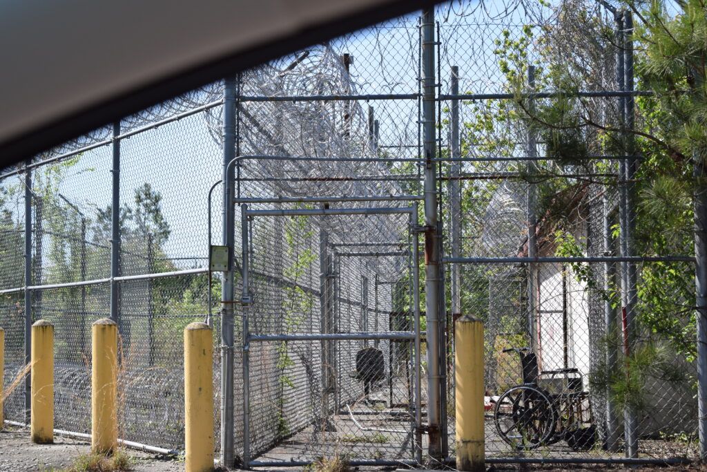 Chain-link security gates and razor wire surrounding the abandoned Scott State Prison in Milledgeville, Georgia.