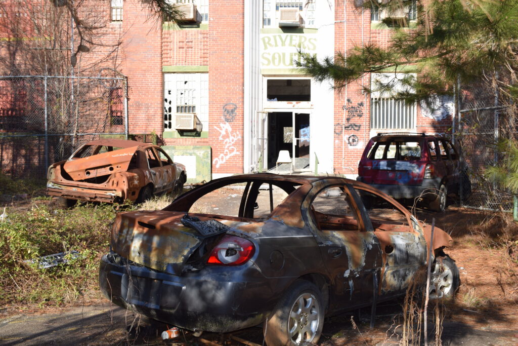 Burned-out cars sit outside the abandoned entrance to Rivers State Prison on the former Central State Hospital campus in Milledgeville, Georgia.