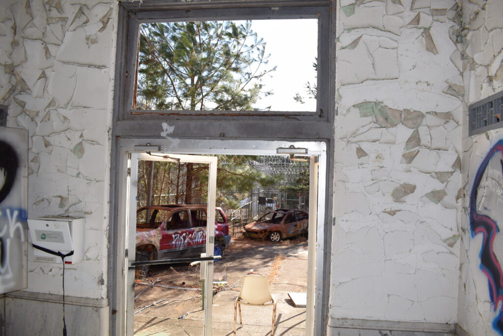 The abandoned entrance of Rivers State Prison looks out toward burned-out vehicles and the overgrown grounds of the former prison in Milledgeville, Georgia.