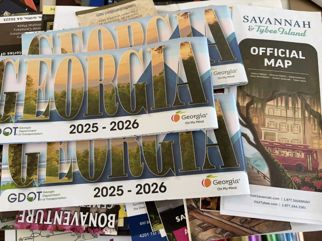 A collection of Georgia travel brochures, official state maps, and Savannah visitor guides gathered at the Georgia Welcome Center.