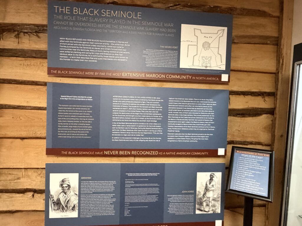 Interpretive exhibit inside the Fort King Visitor Center explaining the history of the Black Seminoles and their role in the Second Seminole War, including illustrations of Abraham and John Horse.