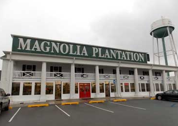 Front entrance of the Magnolia Plantation roadside attraction in Georgia with its large green sign and white-columned storefront.
