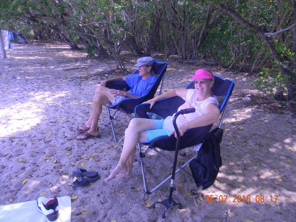 Couple relaxing in folding chairs beneath the trees at Combate Beach in Cabo Rojo, Puerto Rico.
