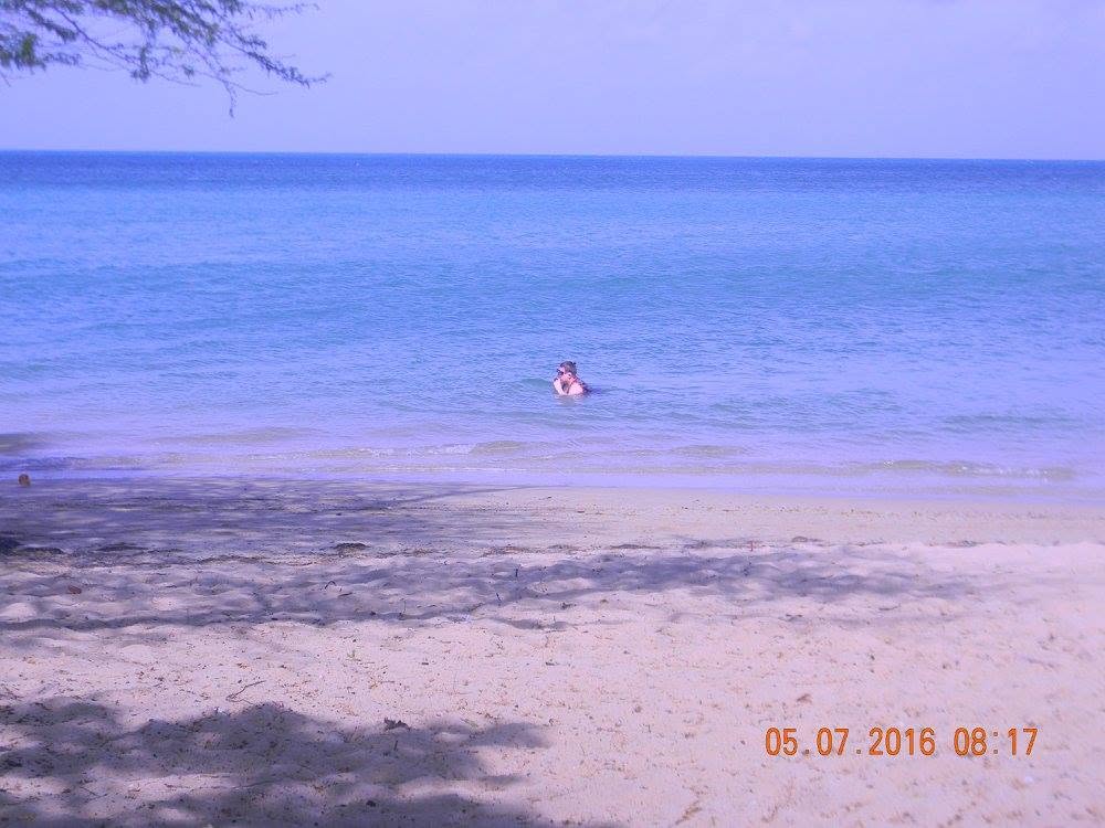 Person swimming in calm blue Caribbean water beside the sandy shore of Combate Beach in Cabo Rojo, Puerto Rico.