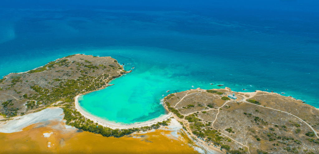 Aerial view of Playa Sucia's crescent beach, turquoise water, and Los Morrillos Lighthouse in Cabo Rojo, Puerto Rico.