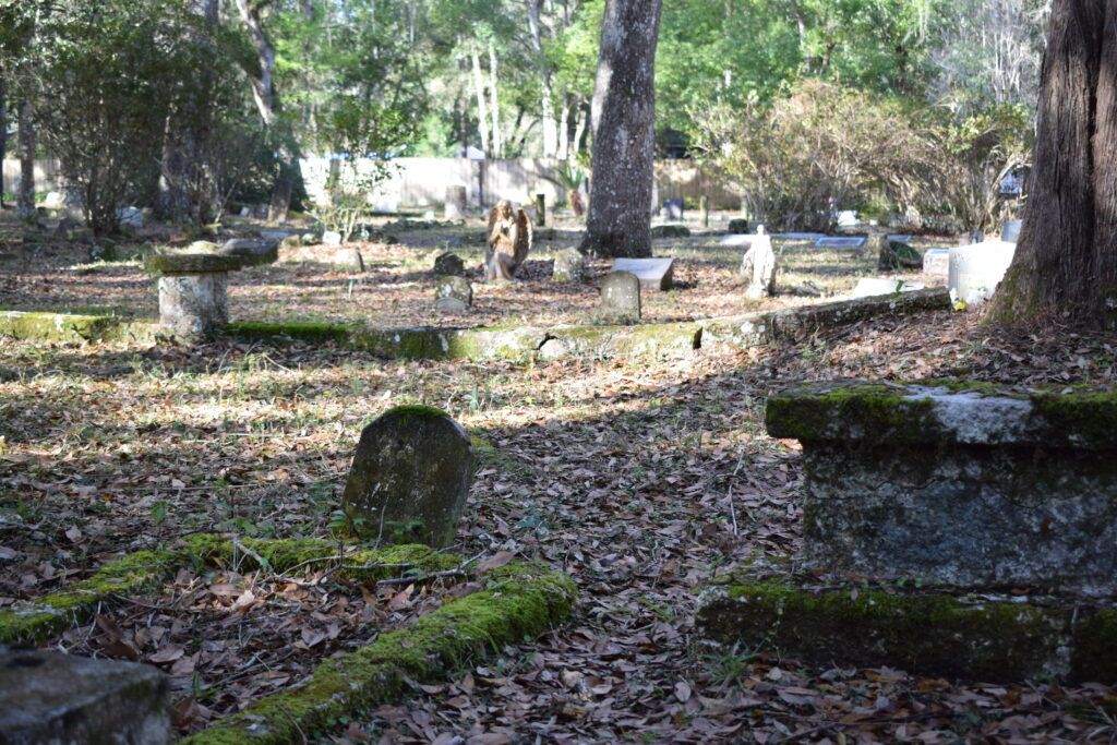 Moss-covered grave markers and historic monuments among the trees at Micanopy Historic Cemetery in Florida