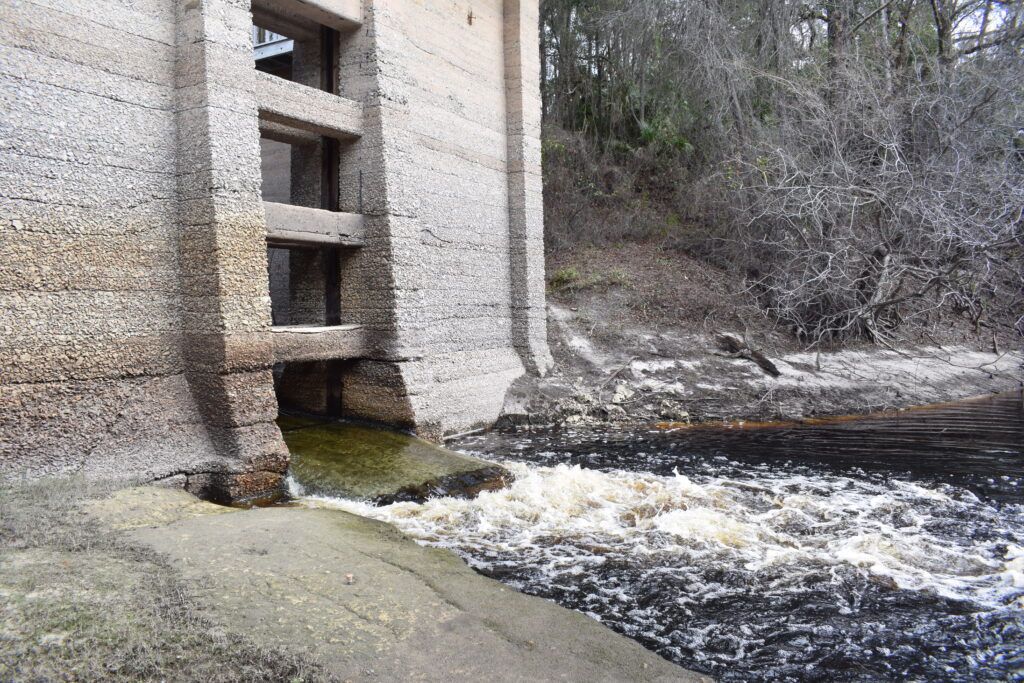 Water flowing beside the concrete walls of the historic White Springs Sulfur Bathhouse into the Suwannee River in White Springs, Florida.