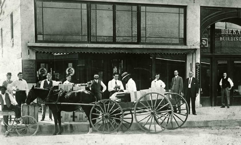 Historic photograph of people and a horse-drawn delivery wagon outside the Dreka Building in DeLand, Florida.