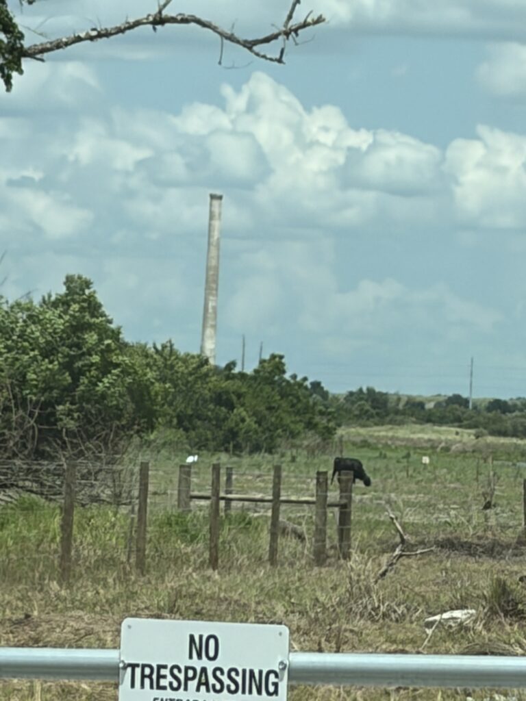 Old Brewster power plant smokestack visible beyond a no trespassing sign at the former Brewster, Florida townsite.