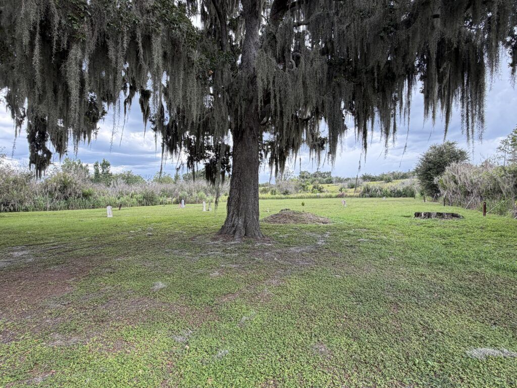 Large oak draped in Spanish moss overlooking scattered historic graves at Crum-Durrance Cemetery in Polk County, Florida.