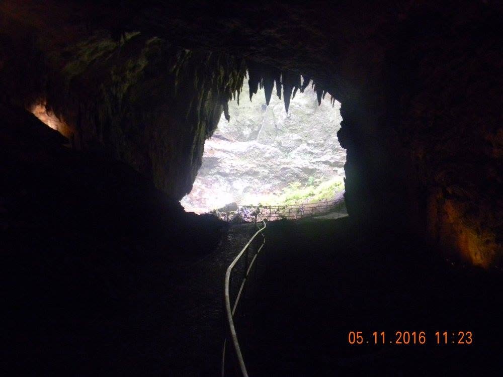 Walking path leading from the dark interior of the Río Camuy Caves toward daylight in Puerto Rico.