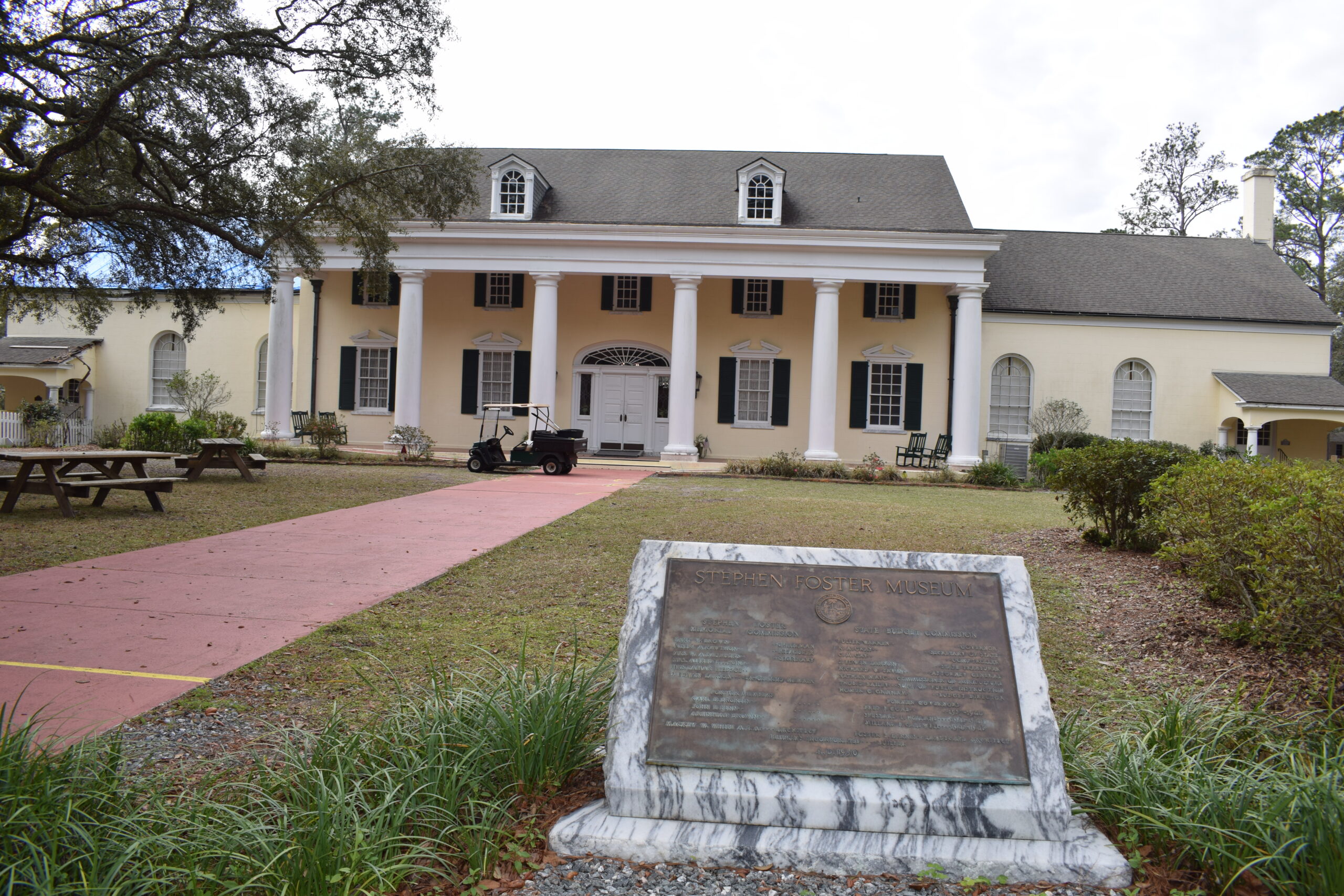 Stephen Foster Museum with tall white columns and a memorial plaque at Stephen Foster Folk Culture Center State Park in White Springs, Florida.