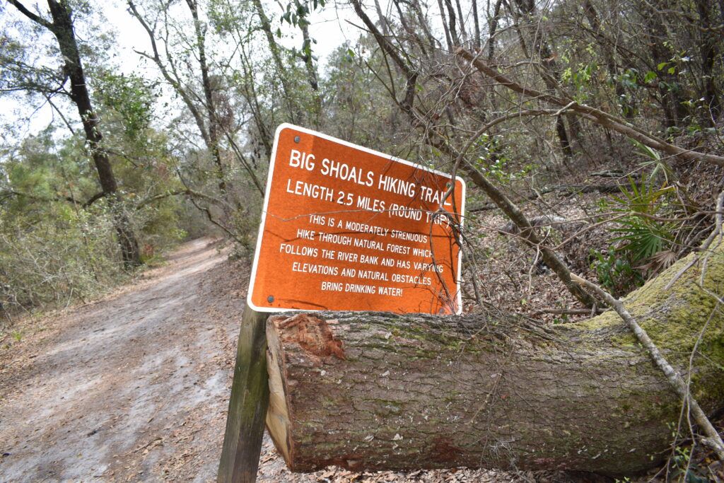 Big Shoals Hiking Trail sign beside the wooded trail at Big Shoals State Park near White Springs, Florida.