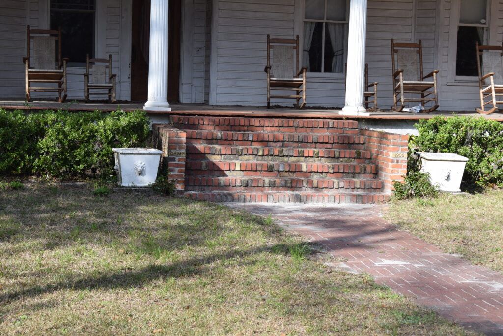Brick steps marked 1906 leading to a porch with rocking chairs at a historic home in White Springs, Florida.