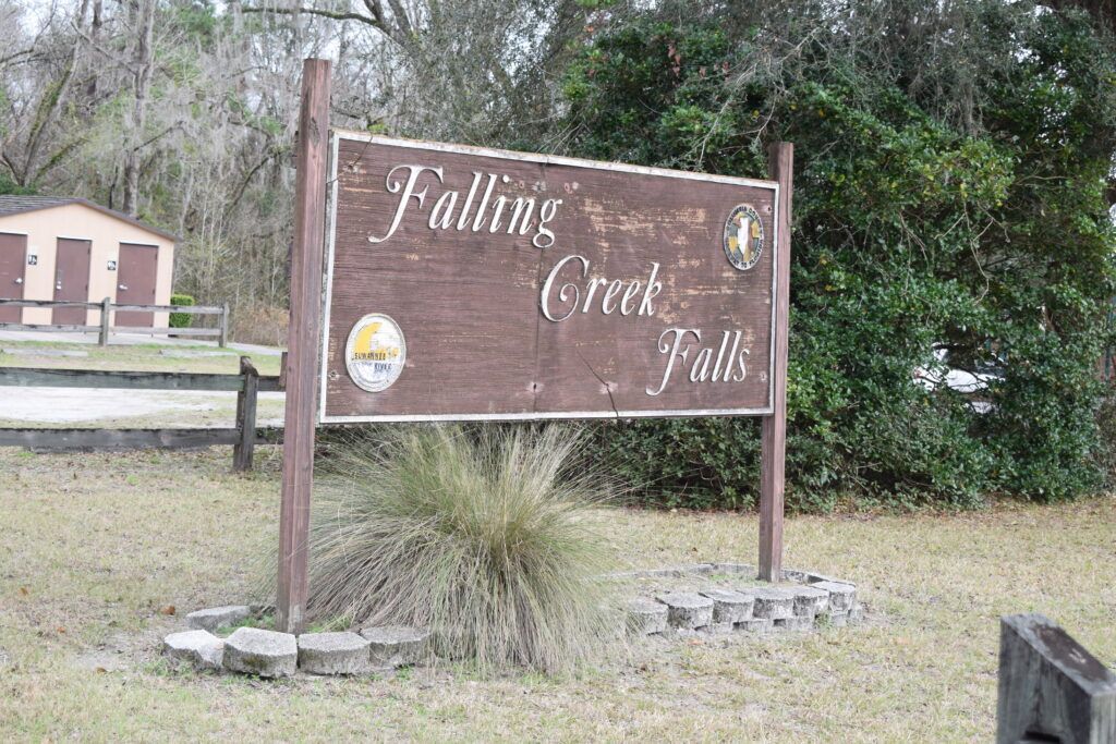 Wooden Falling Creek Falls entrance sign surrounded by trees near Lake City, Florida.